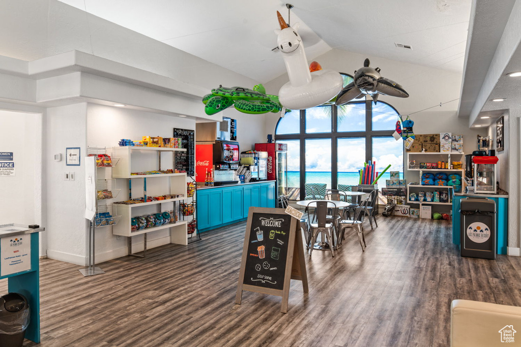 Recreation room with baseboards, high vaulted ceiling, visible vents, and wood finished floors