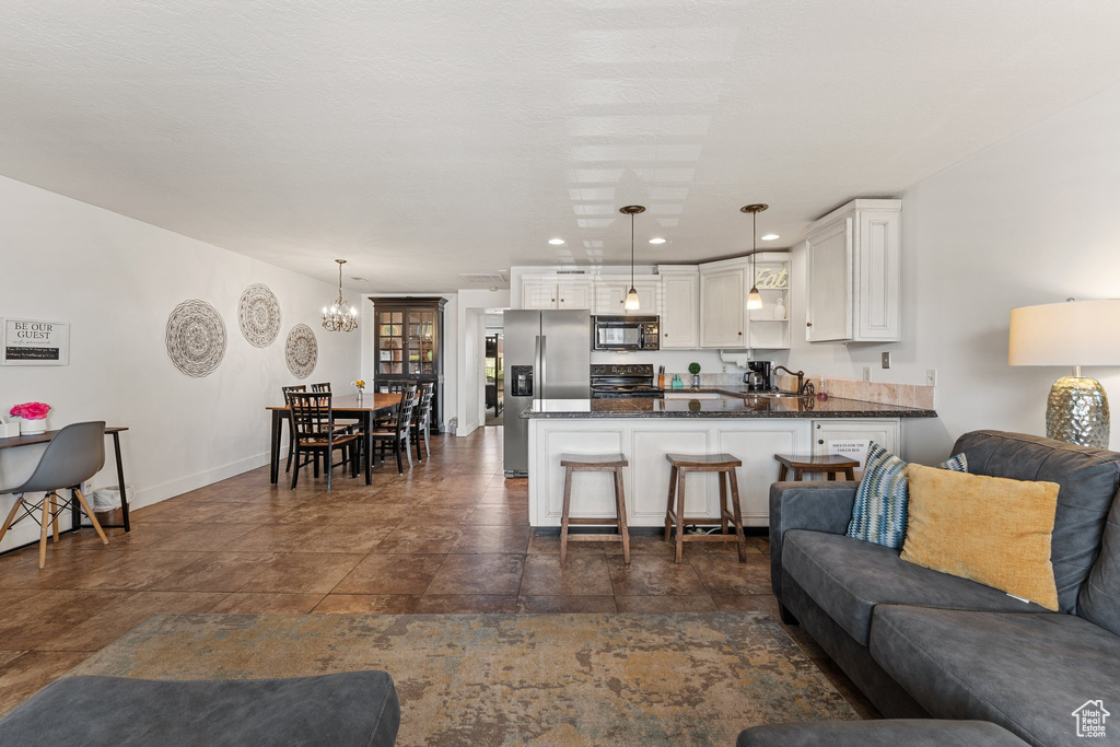 Living room with recessed lighting, an inviting chandelier, stone finish floor, and baseboards