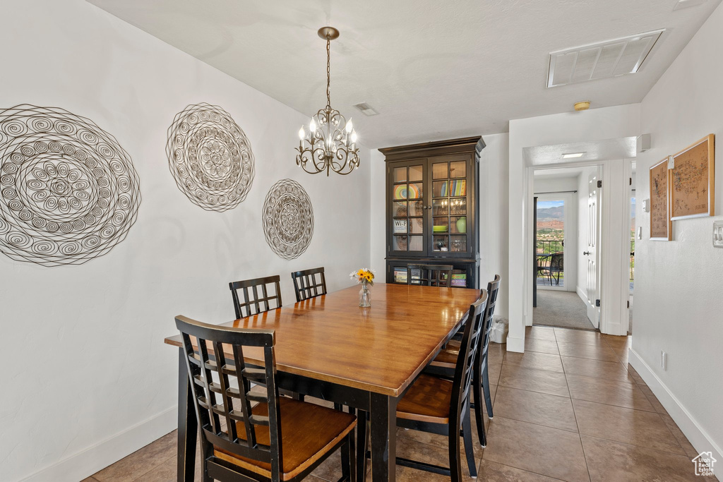 Tiled dining room with visible vents, a chandelier, and baseboards