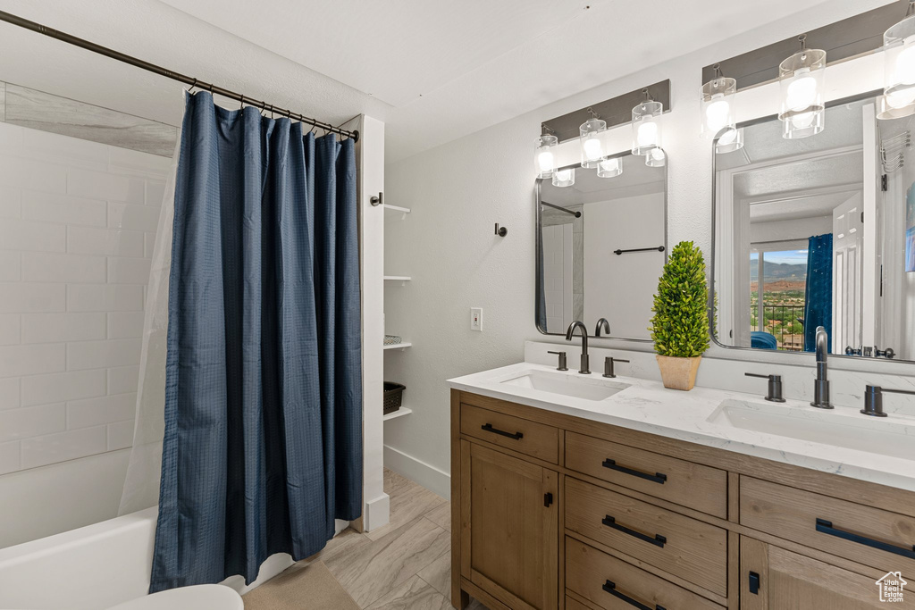Full bathroom featuring double vanity, shower / bath combo with shower curtain, and a sink