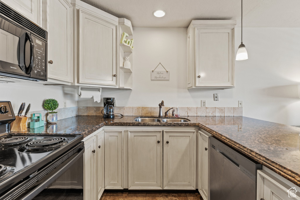 Kitchen featuring dark stone countertops, open shelves, a sink, black appliances, and decorative light fixtures