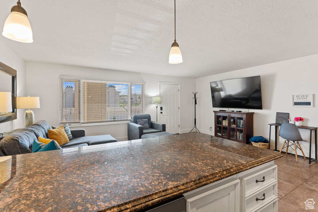 Kitchen with decorative light fixtures, open floor plan, white cabinetry, and a textured ceiling