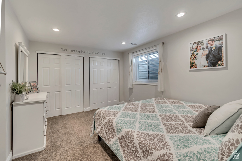 Carpeted bedroom featuring visible vents, recessed lighting, and two closets