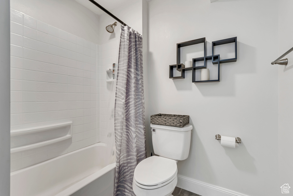 Full bathroom featuring baseboards, toilet, and shower / tub combo with curtain