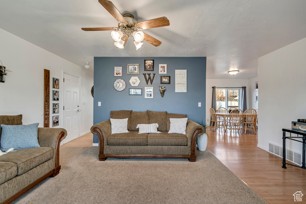Living room featuring baseboards, visible vents, a ceiling fan, and wood finished floors