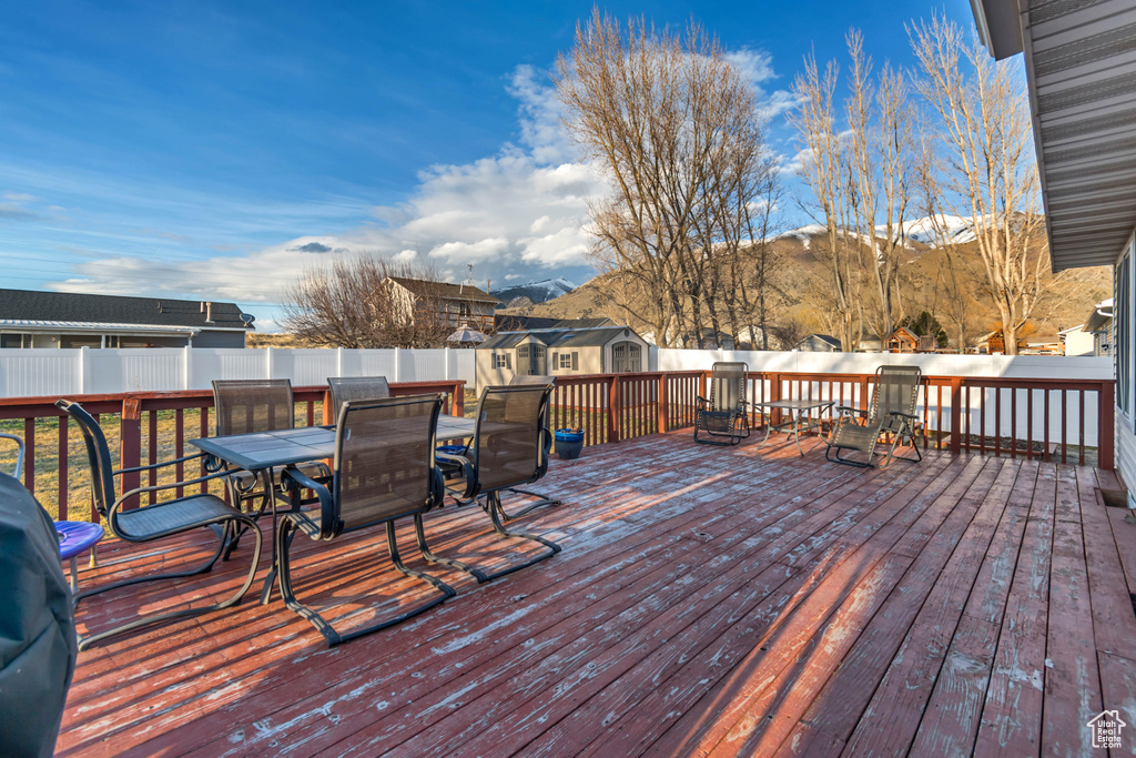 Wooden deck featuring fence, outdoor dining space, and a mountain view