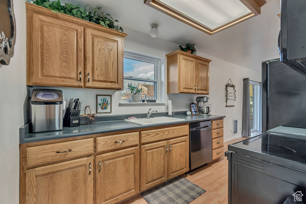 Kitchen featuring visible vents, dark countertops, a sink, light wood-style floors, and black appliances