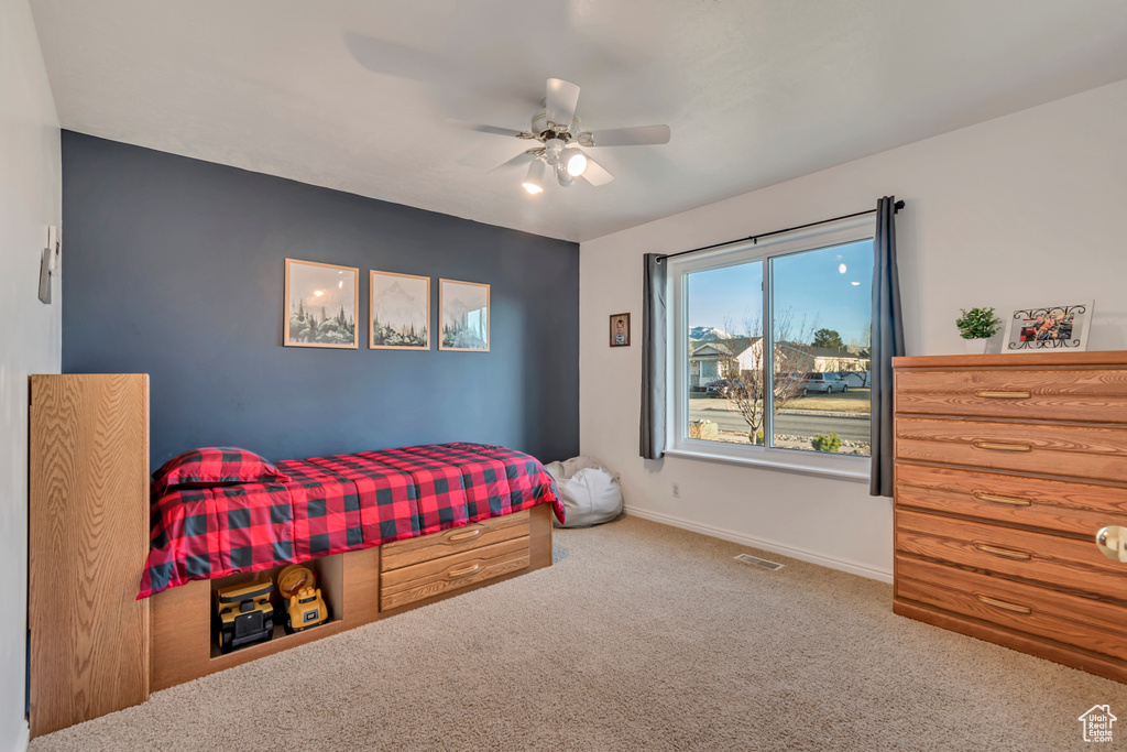 Carpeted bedroom featuring baseboards, visible vents, and a ceiling fan