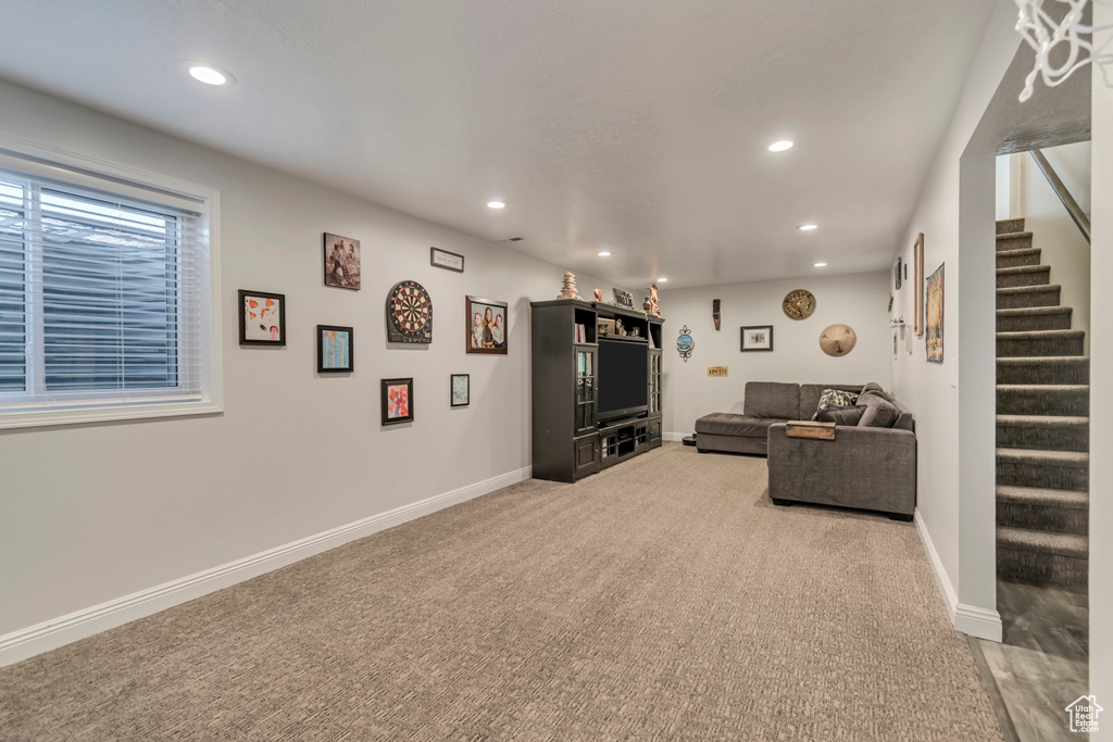 Living room with stairs, light colored carpet, baseboards, and recessed lighting