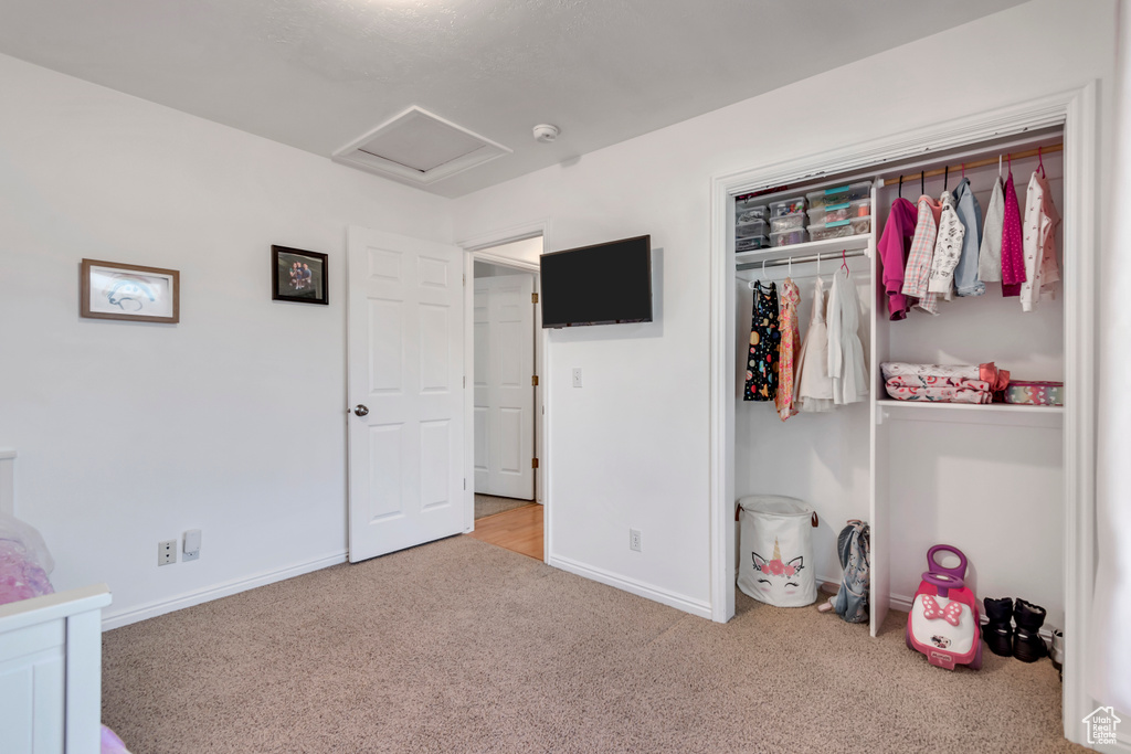 Carpeted bedroom with attic access, baseboards, and a closet