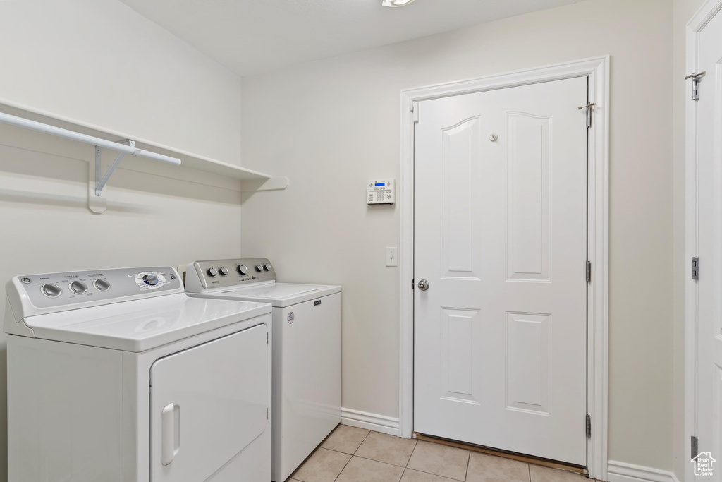 Laundry area with light tile patterned flooring, baseboards, laundry area, and separate washer and dryer