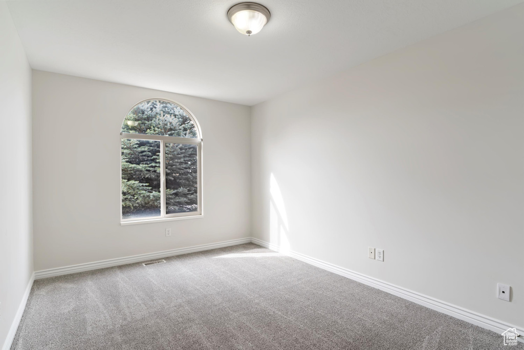 Spare room featuring carpet floors, baseboards, and visible vents