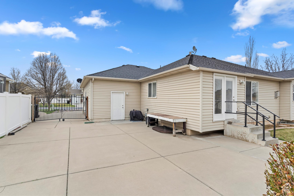 Back of property with a gate, fence, and a patio area