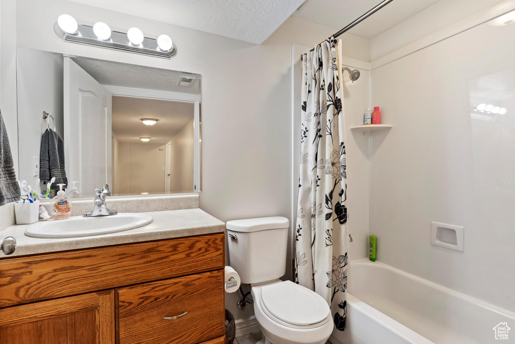 Full bath featuring toilet, shower / bath combo with shower curtain, and vanity