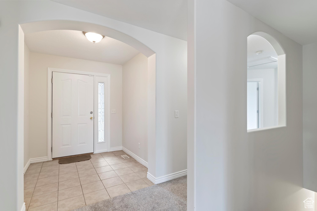 Entrance foyer featuring baseboards, arched walkways, and light tile patterned floors