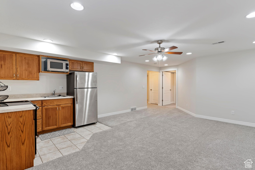 Kitchen with light countertops, visible vents, light carpet, white microwave, and freestanding refrigerator