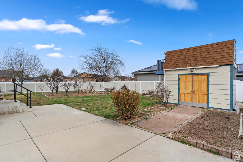 View of patio / terrace with an outdoor structure, a fenced backyard, and a storage shed