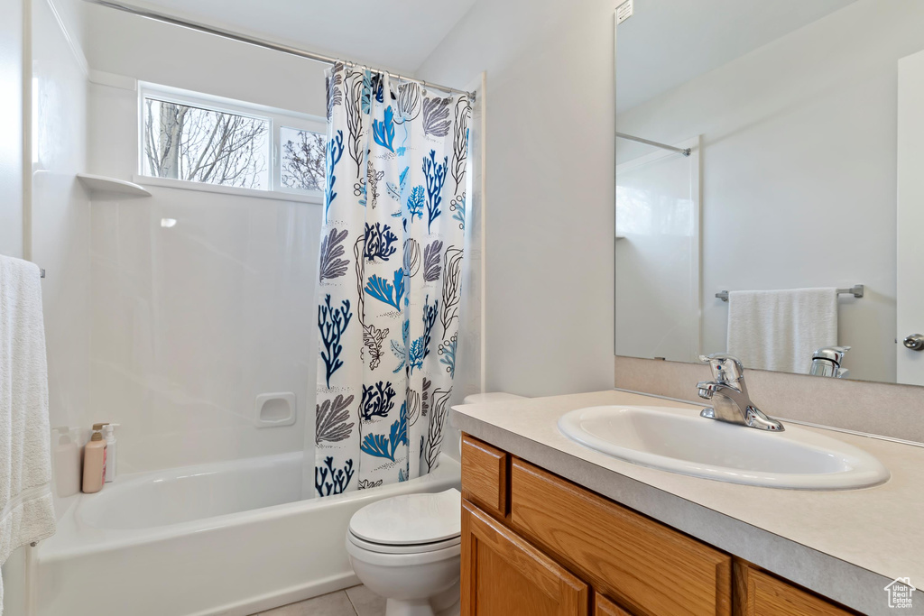 Bathroom featuring tile patterned floors, toilet, vanity, and shower / bath combination with curtain