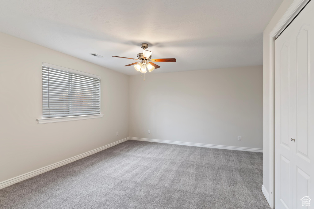 Carpeted spare room with baseboards, ceiling fan, and visible vents