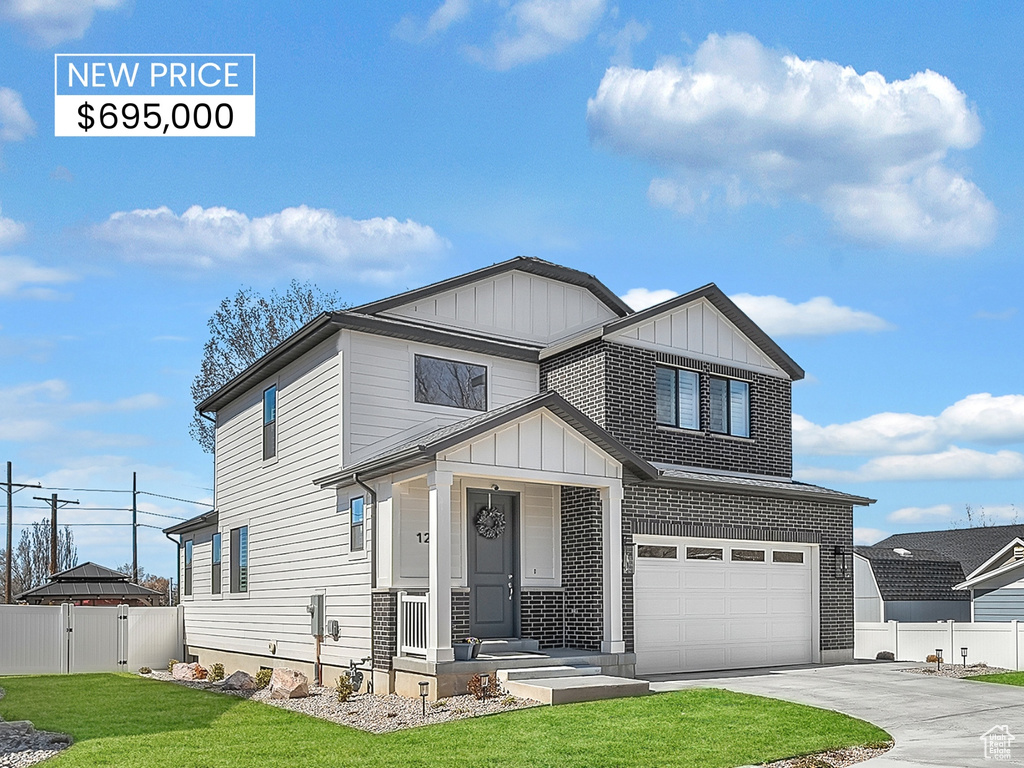 View of front of property featuring board and batten siding, fence, driveway, and a garage