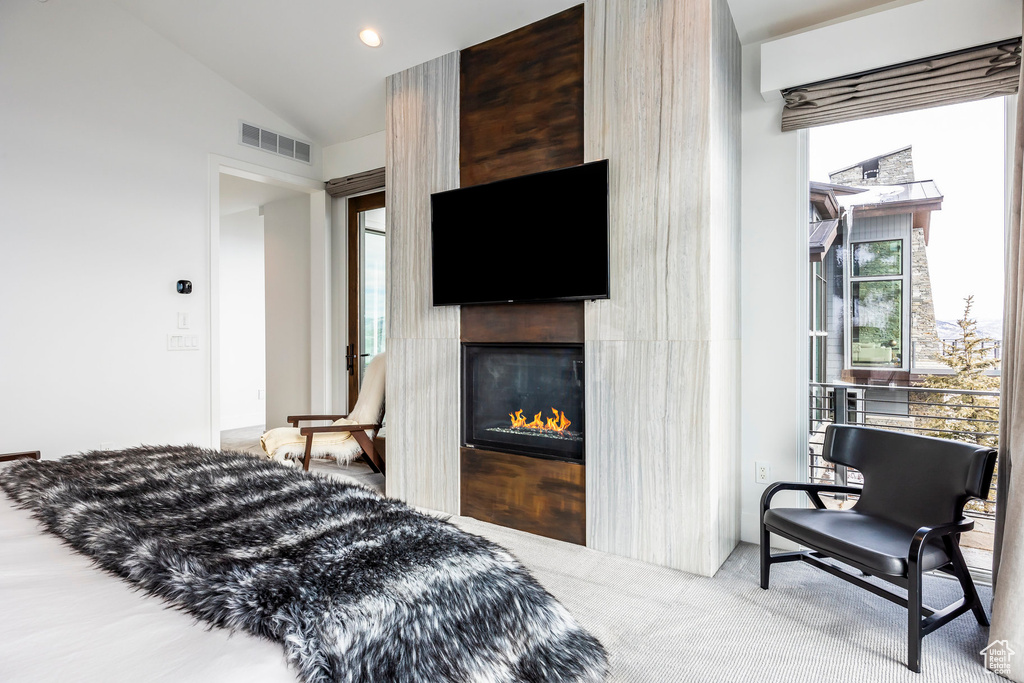 Carpeted bedroom featuring a glass covered fireplace and lofted ceiling