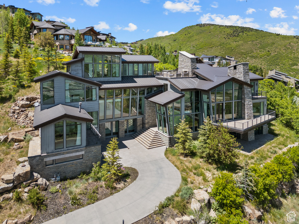 View of front of property featuring a sunroom, stone siding, a mountain view, a standing seam roof, and a metal roof