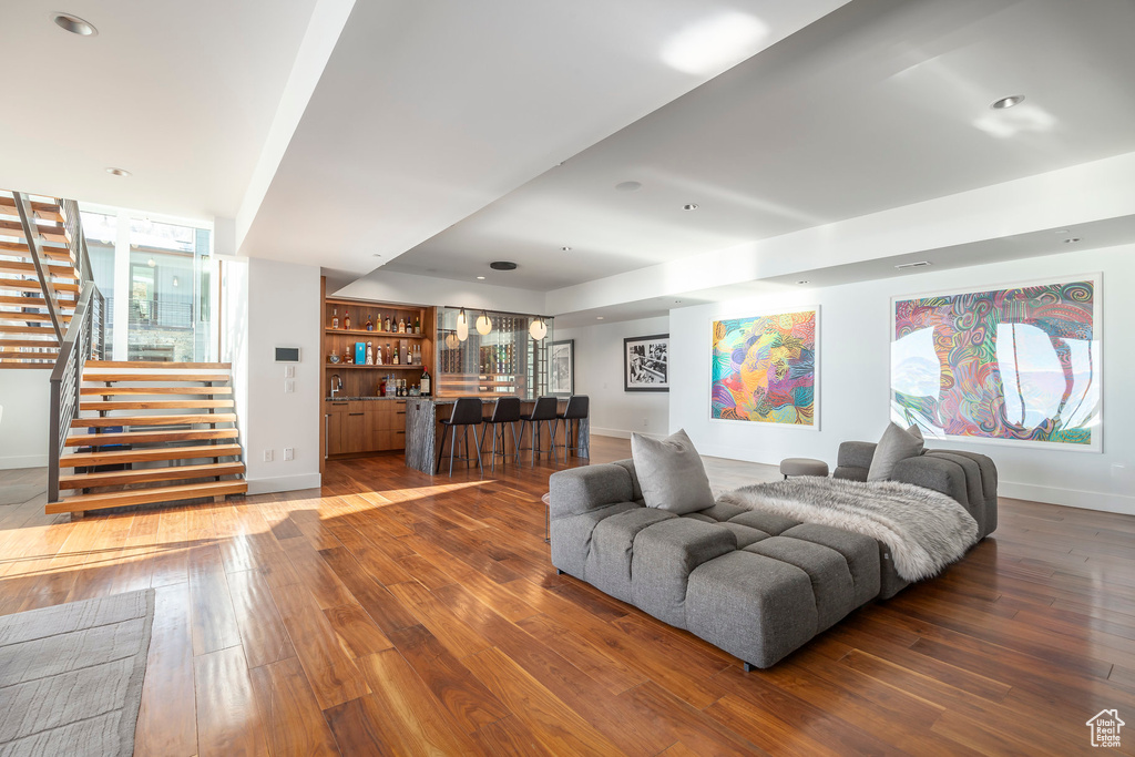 Living area with wet bar, hardwood / wood-style flooring, stairs, and recessed lighting