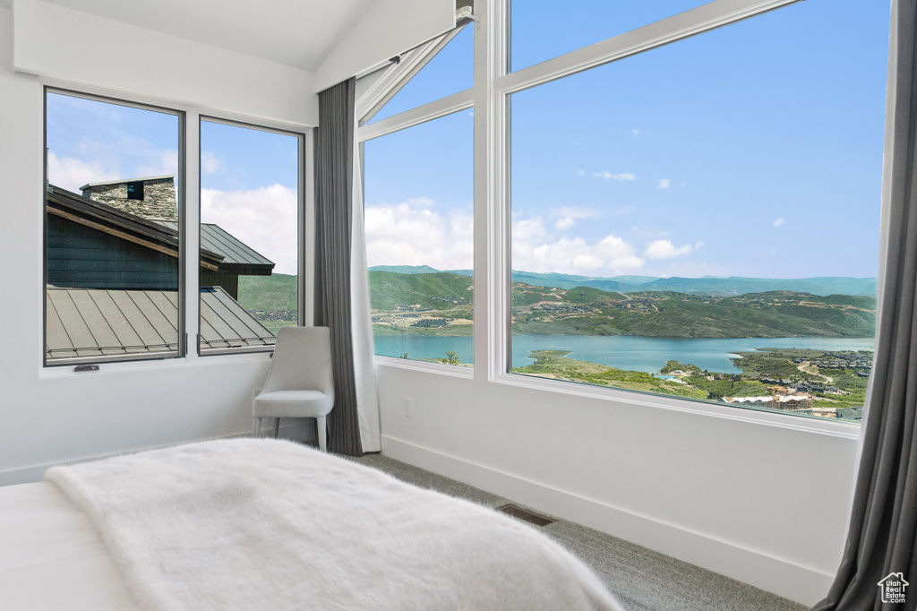Bedroom featuring a water view, carpet flooring, and vaulted ceiling