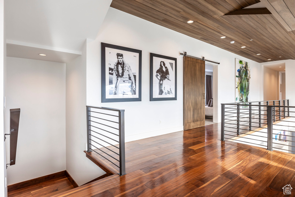 Corridor with an upstairs landing, wood finished floors, a barn door, recessed lighting, and wood ceiling