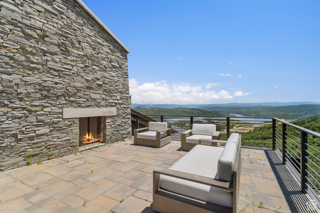 View of patio with a water and mountain view and an outdoor living space with a fireplace