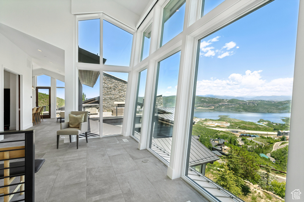 Sunroom / solarium featuring a water view and a high ceiling