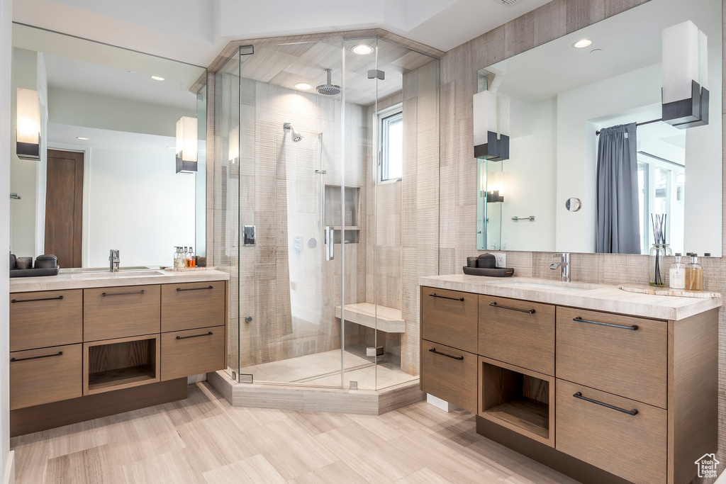 Bathroom featuring a shower stall, two vanities, decorative backsplash, and recessed lighting