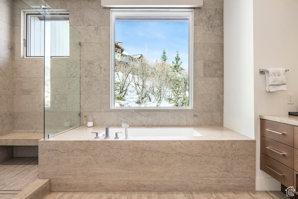Full bath with a bath, vanity, and wood finished floors
