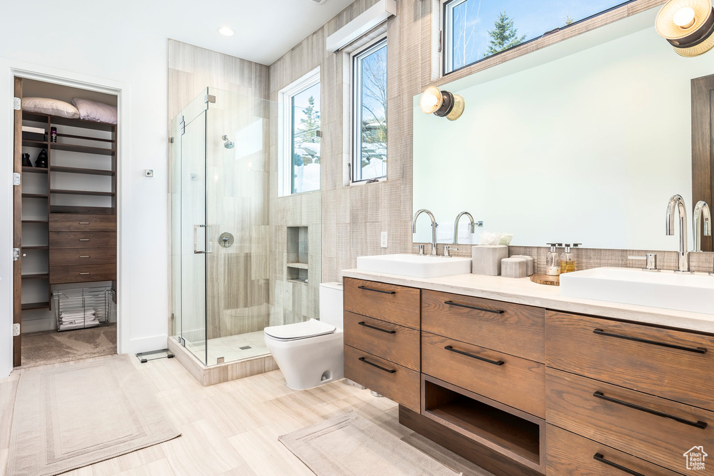 Bathroom featuring a shower stall, a walk in closet, and double vanity