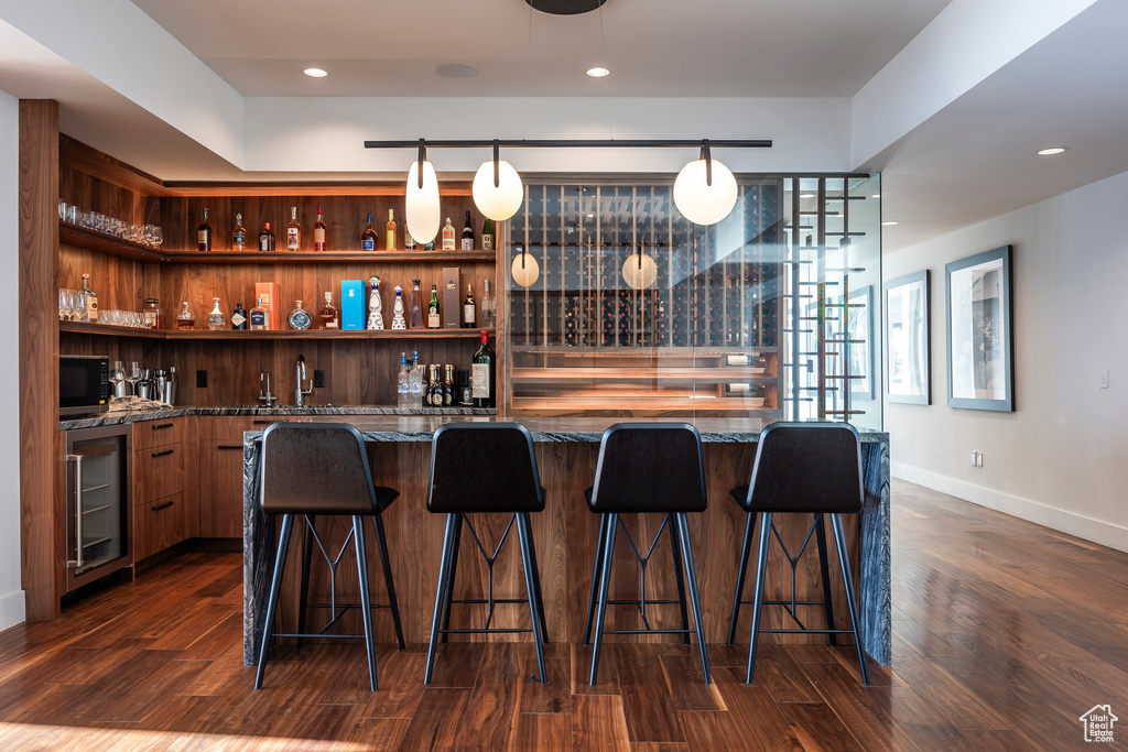 Indoor wet bar with wine cooler, black microwave, dark wood finished floors, and recessed lighting