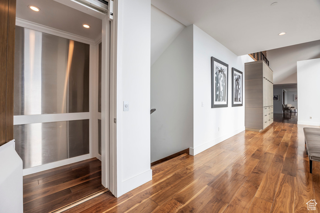Corridor with recessed lighting, wood finished floors, and elevator