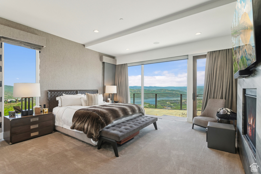 Bedroom featuring carpet flooring, access to outside, a lit fireplace, recessed lighting, and a mountain view
