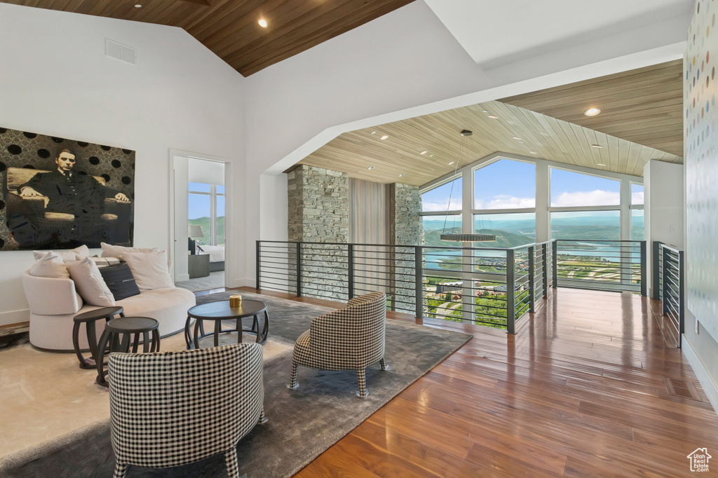 Living area with wood ceiling, high vaulted ceiling, wood finished floors, a water view, and recessed lighting