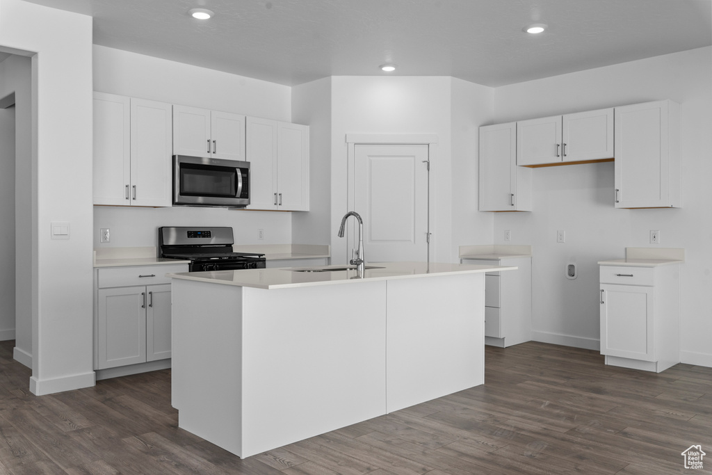 Kitchen with white cabinetry, a center island with sink, appliances with stainless steel finishes, and dark wood finished floors
