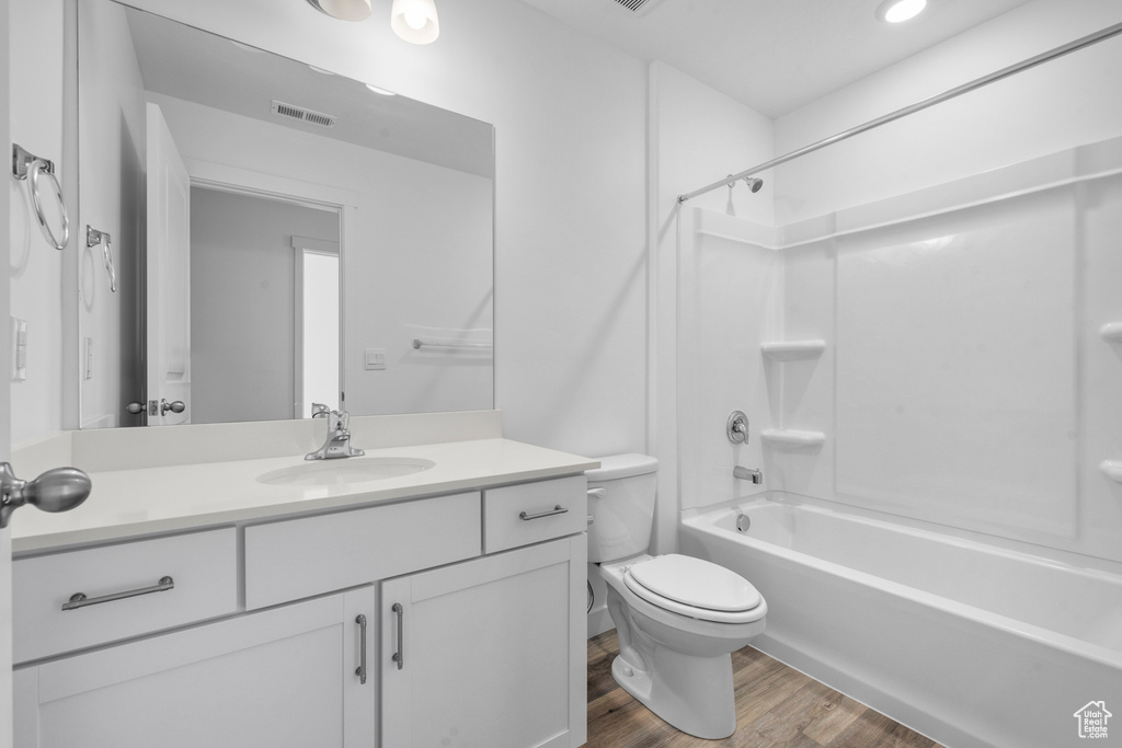 Full bathroom with toilet, vanity, shower / tub combination, wood finished floors, and visible vents