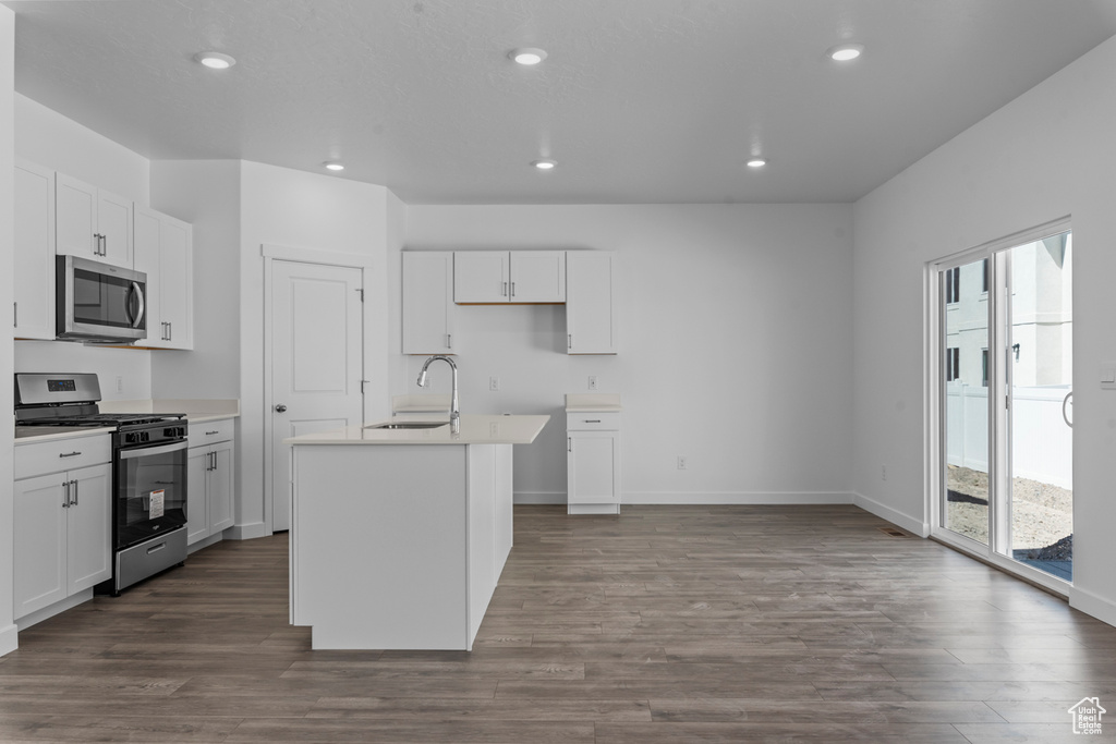 Kitchen with white cabinetry, recessed lighting, dark wood-type flooring, a kitchen island with sink, and appliances with stainless steel finishes