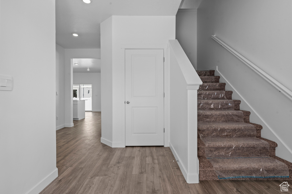Stairs with baseboards, wood finished floors, and recessed lighting