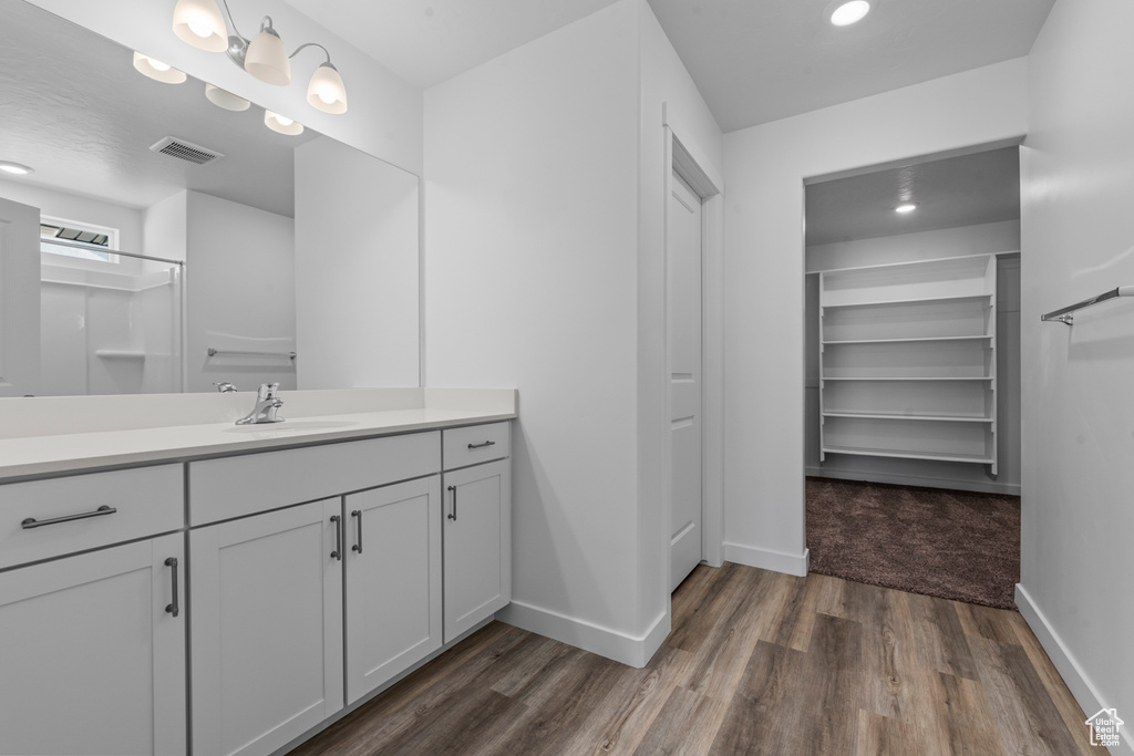 Bathroom with vanity, wood finished floors, baseboards, visible vents, and recessed lighting