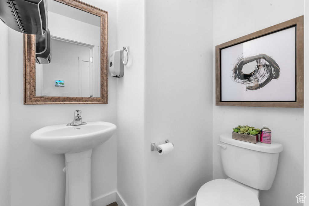 Half bath with baseboards, toilet, and a sink