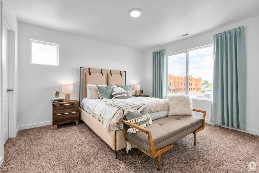 Carpeted bedroom featuring multiple windows, visible vents, and baseboards
