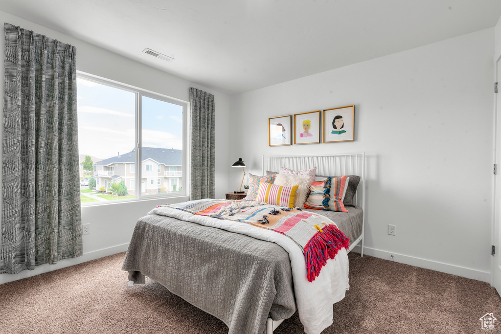 Carpeted bedroom featuring baseboards and visible vents