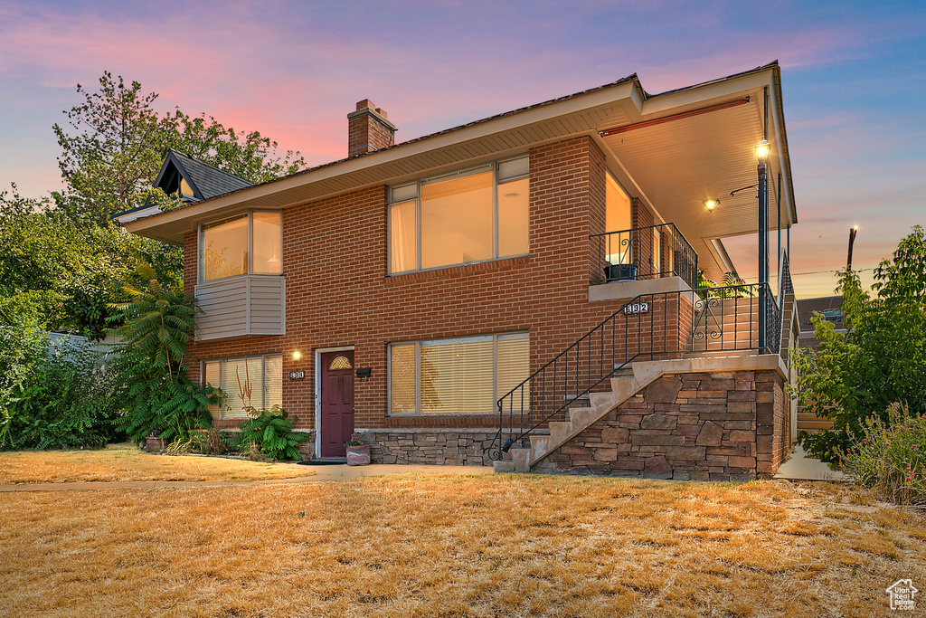 View of front of property with a chimney, stairs, and brick siding