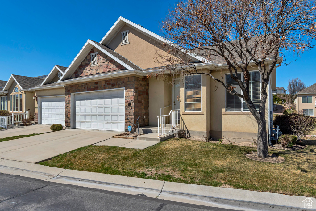 View of front of property featuring stone siding, a garage, a front yard, stucco siding, and driveway