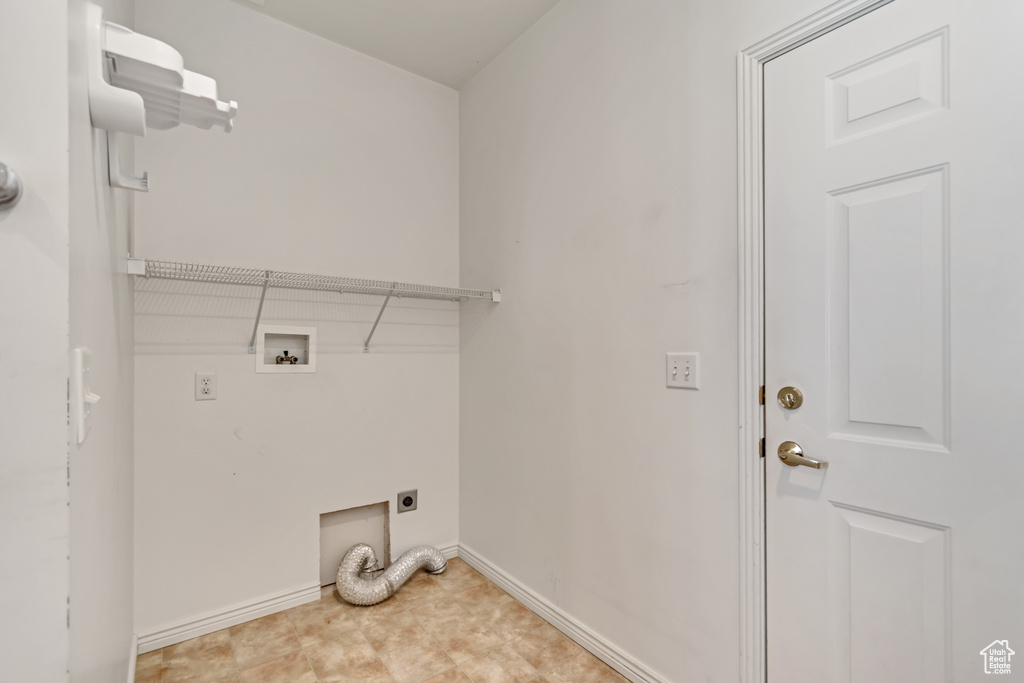 Washroom with electric dryer hookup, hookup for a washing machine, baseboards, and laundry area