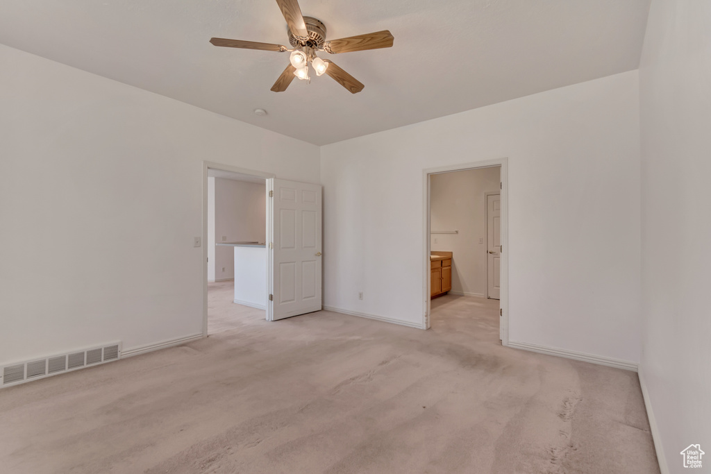 Unfurnished bedroom with light carpet, baseboards, ensuite bathroom, and visible vents
